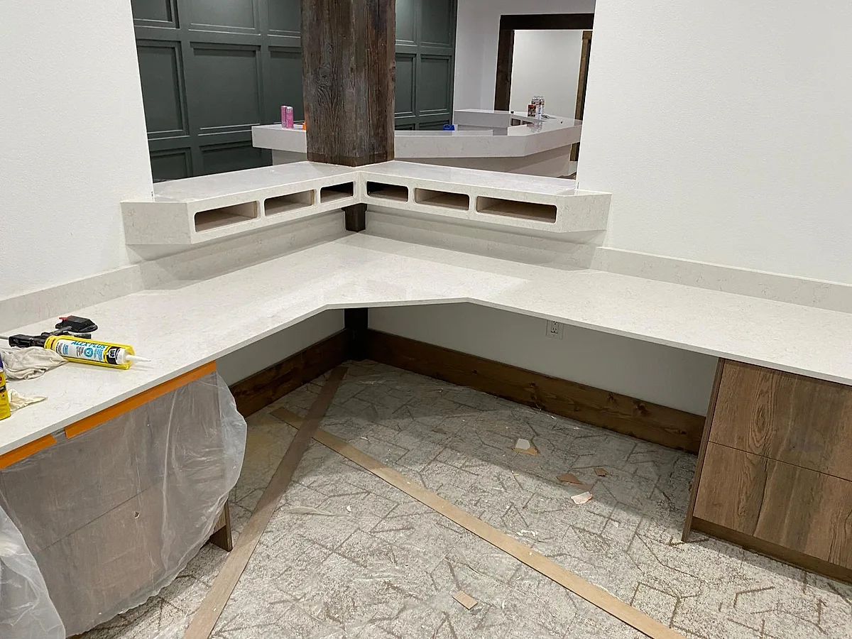 The same reception desk mid-build — quartz tops being set over the framed base