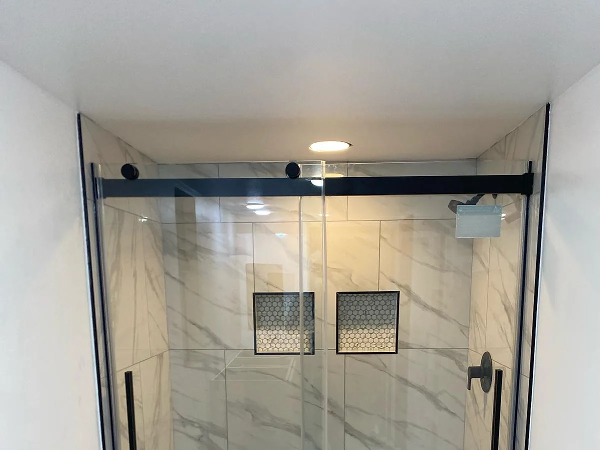 Frameless glass shower with a marble-look stone surround