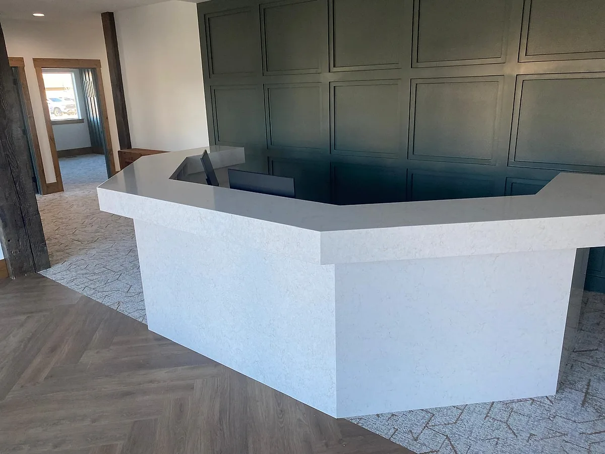 Finished custom bar with an angular quartz countertop against a paneled wall