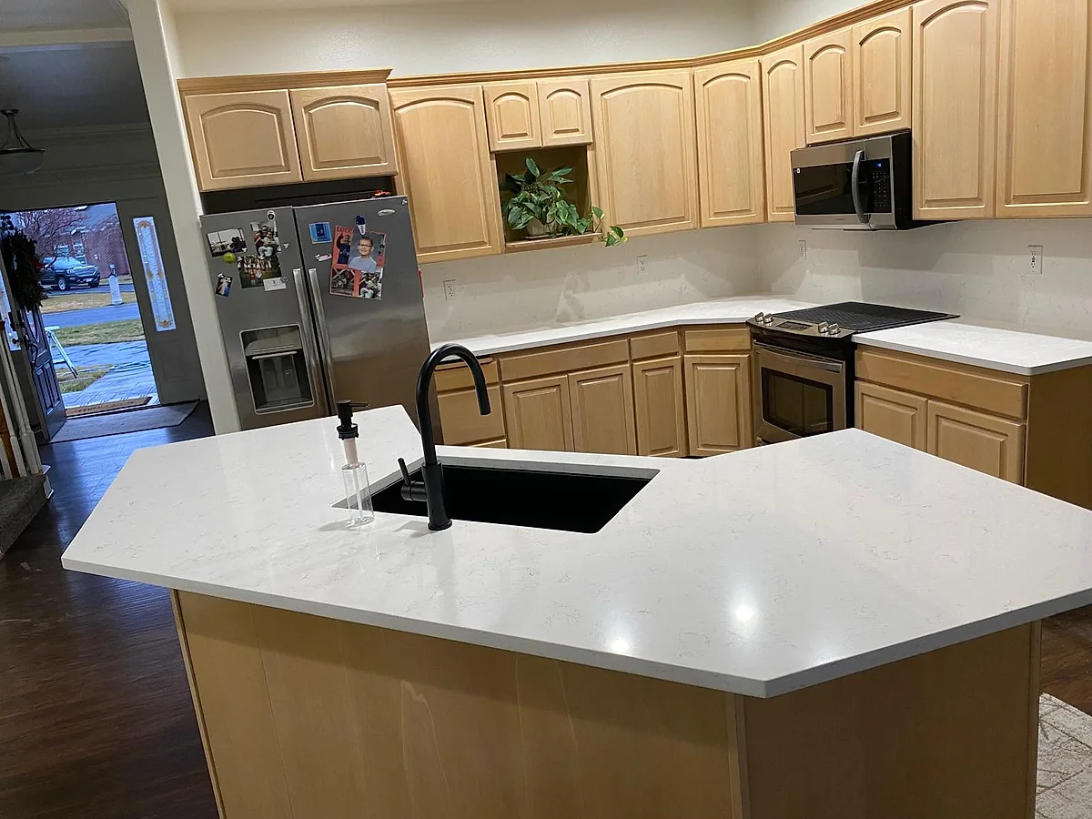 Finished kitchen with a white quartz island, black faucet and wood cabinetry