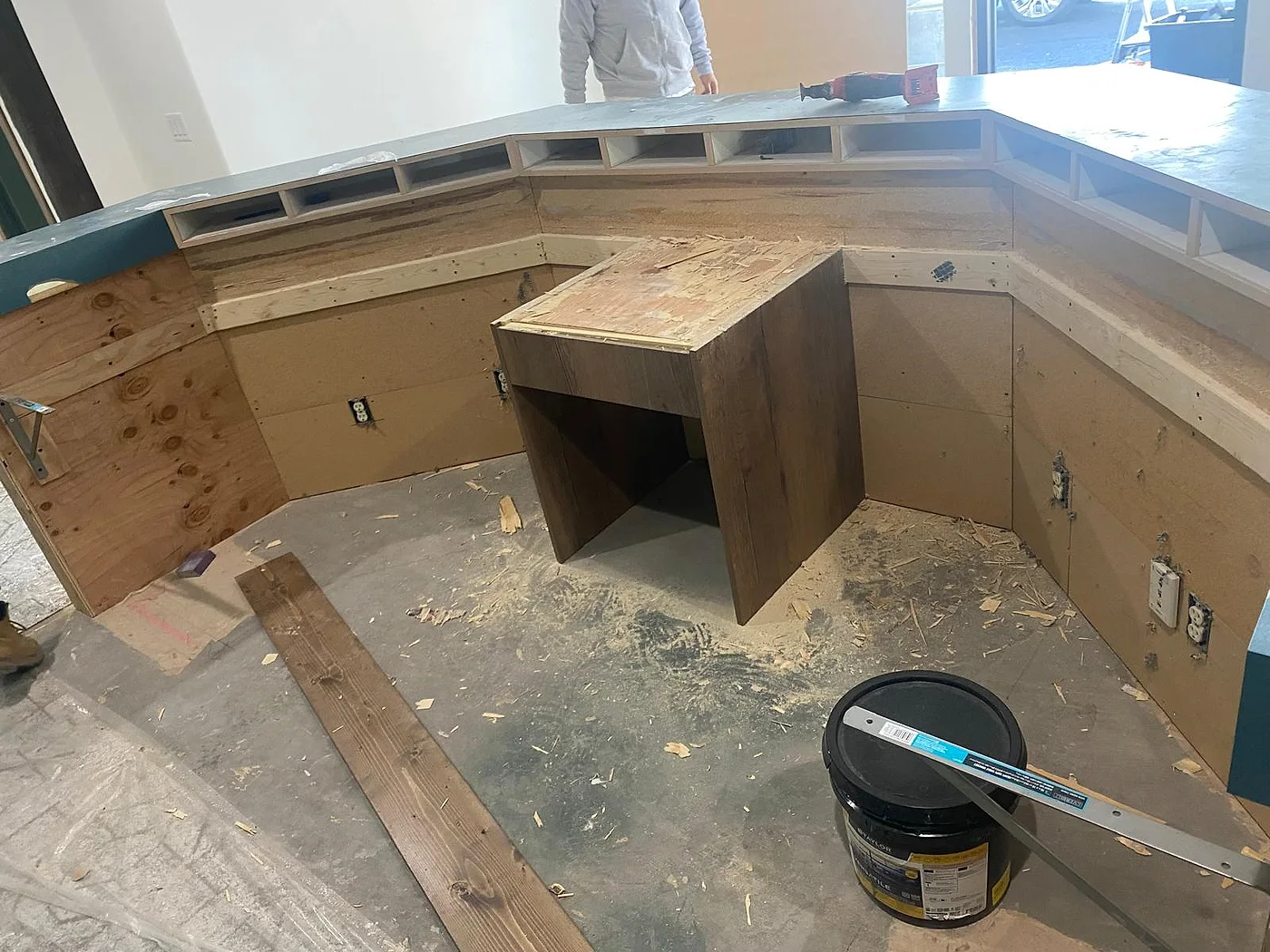 Curved reception desk during construction — exposed framing and substrate