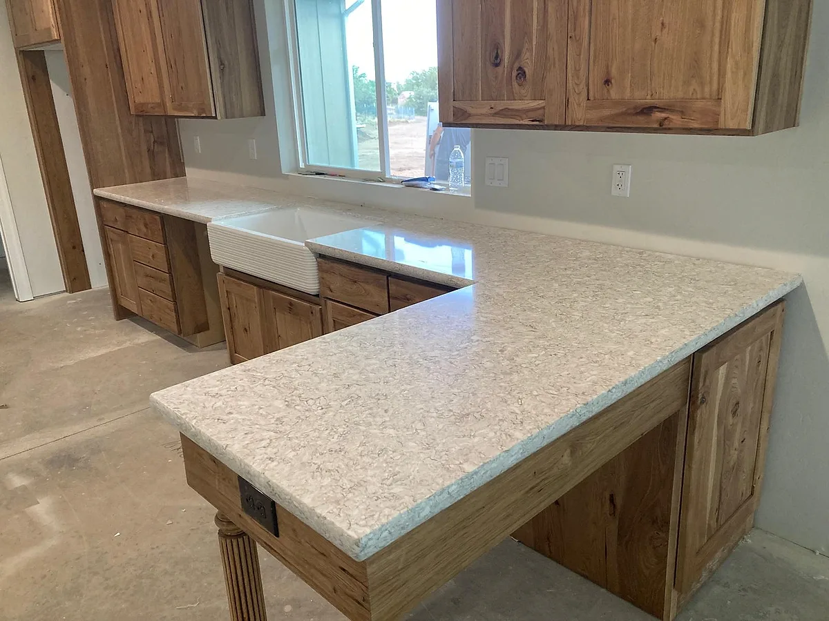 Light granite countertops with a farmhouse sink and wood cabinets